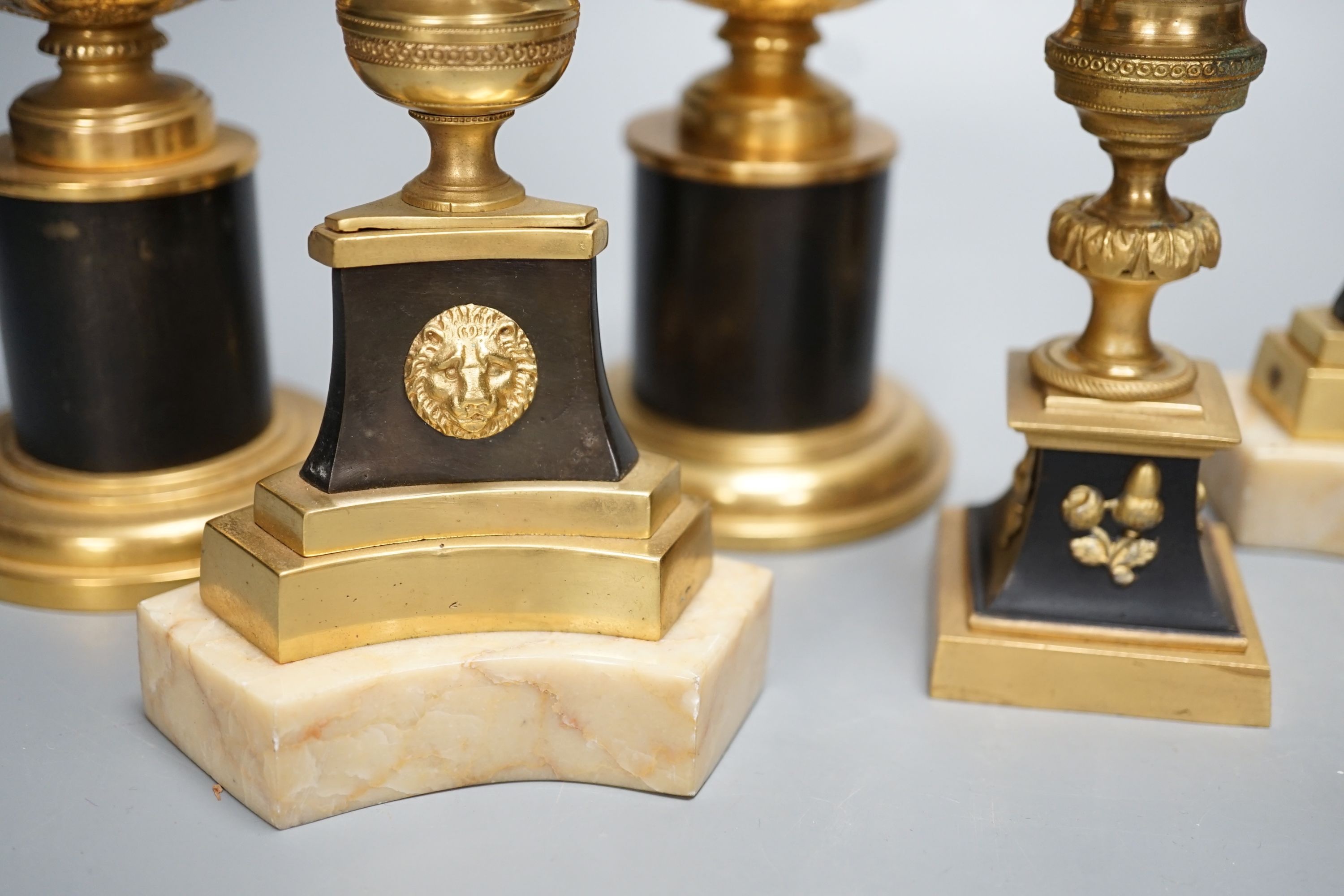 A pair of Louis XVI style ormolu and bronze models of campana urns and two similar pairs of Empire style candlesticks